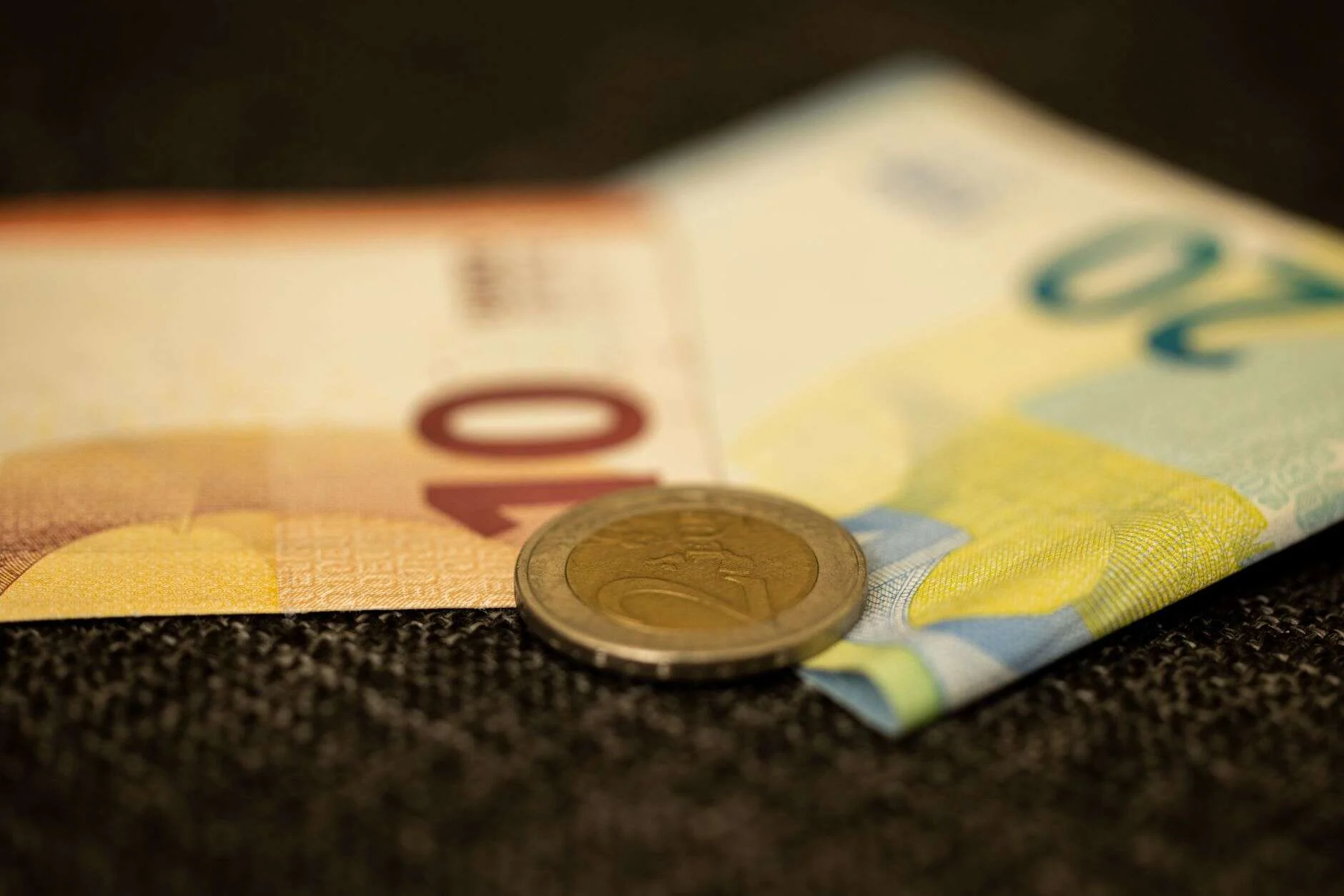 Primer plano de billetes y una moneda de euro
