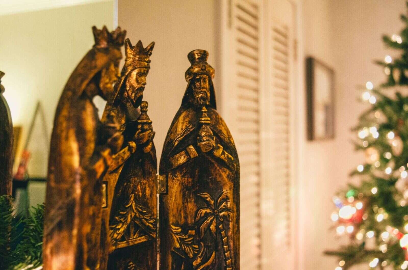Figuras de los Reyes Magos con luces de árbol desenfocadas