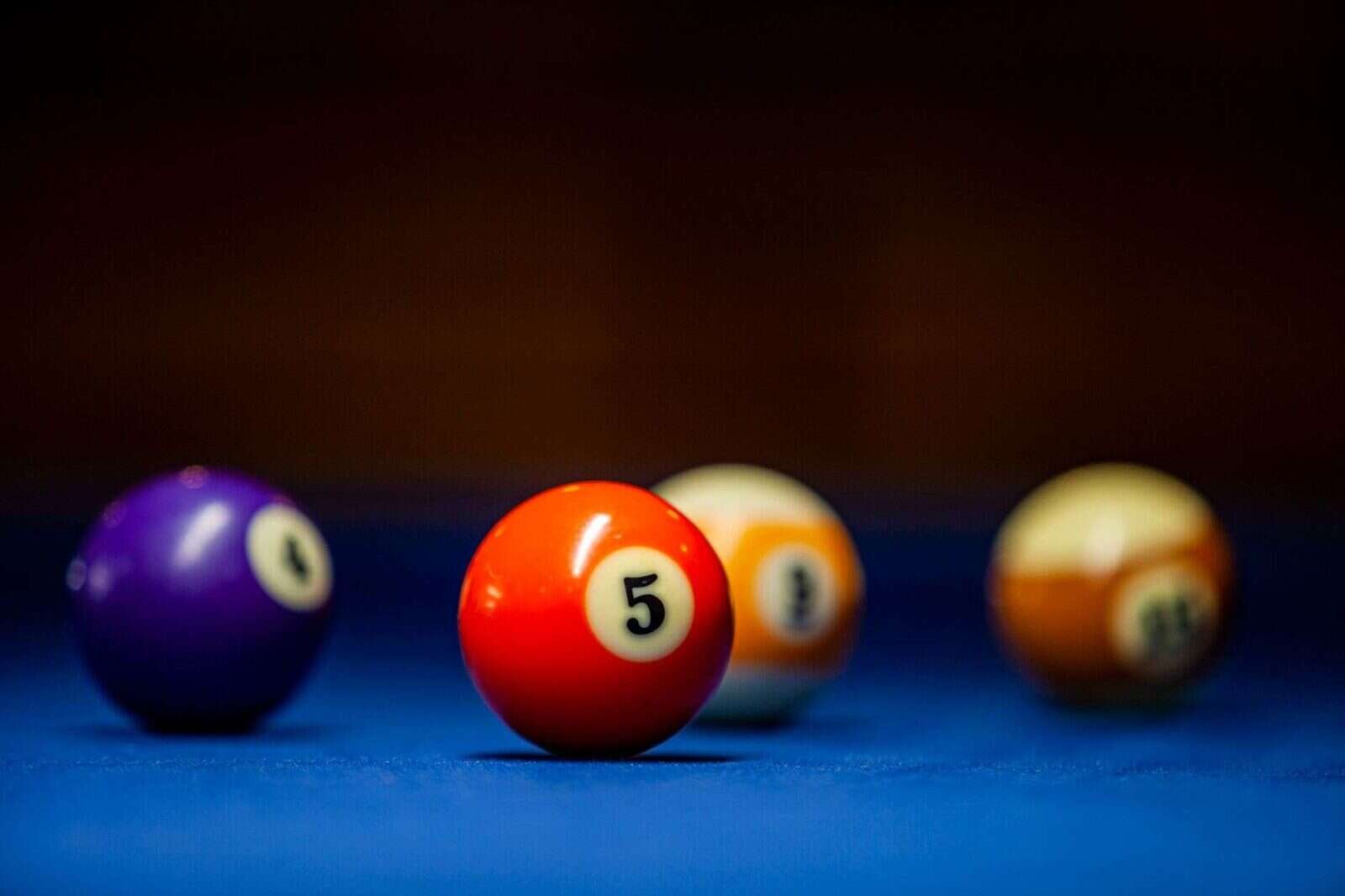 Bolas de colores numeradas sobre una mesa azul con el número cinco en primer plano