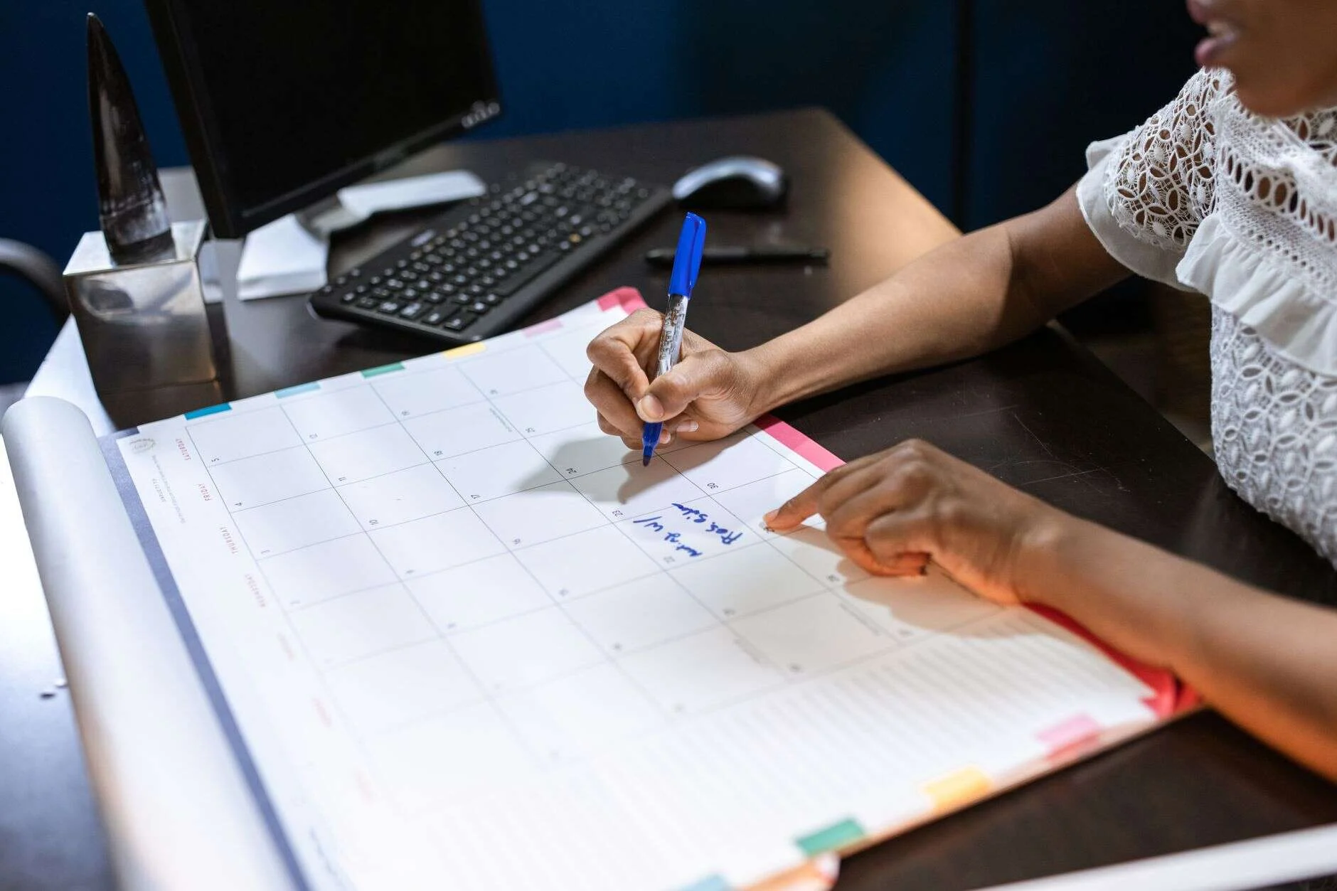 Persona anotando una fecha en un calendario de escritorio