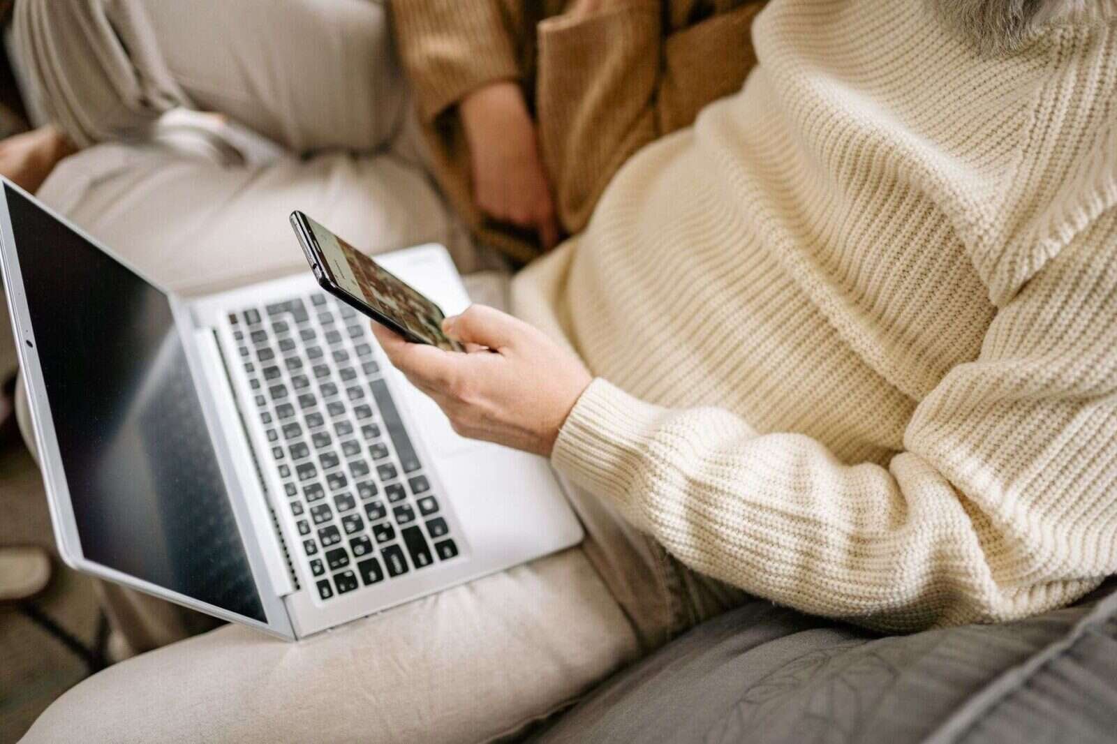 Persona usando el móvil y el ordenador portátil en casa