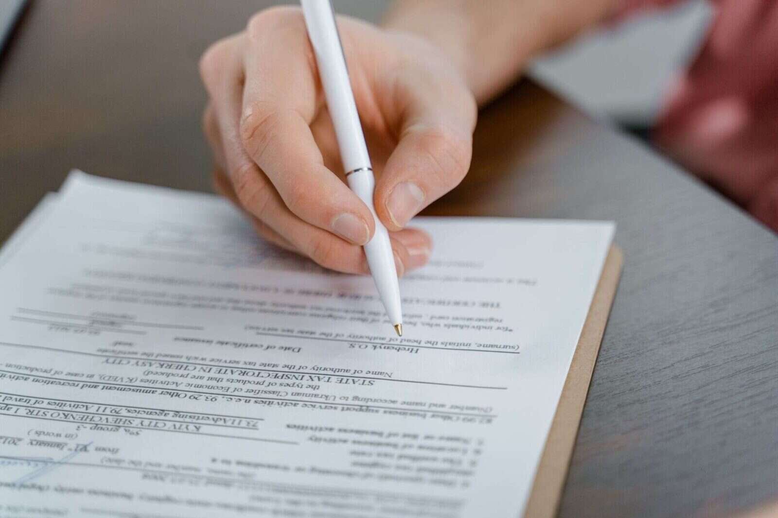 Mano con bolígrafo rellenando un papel